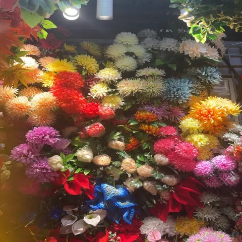 Colorful artificial chrysanthemums та decorative flower stems displayed on a wall.