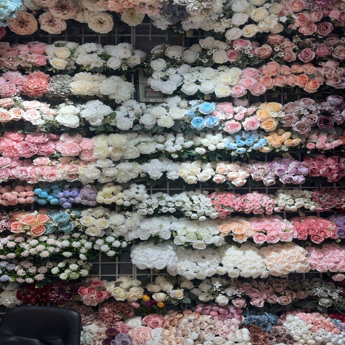 Large display of artificial flowers including roses, hydrangeas, та peonies in multiple colors.